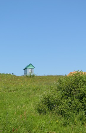 A lone house stands on a green grass hillの写真素材