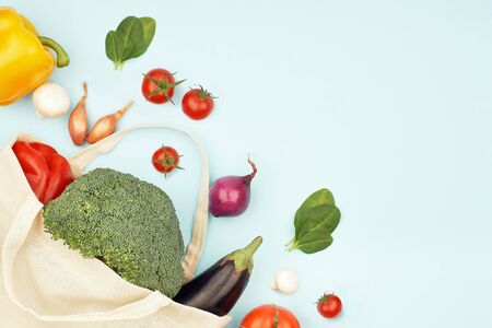 Canvas eco bag with vegetables on light blue background. Creative green composition flat lay viewの写真素材