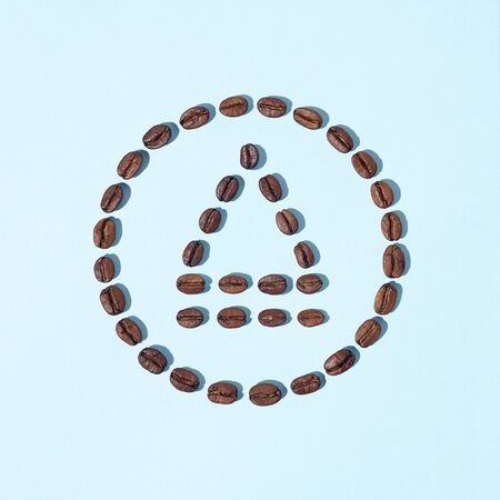 Eject symbol made from fresh roasted arabica coffee beans on light blue background. Creative minimal flat layの写真素材