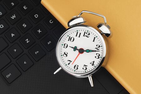 Metal vintage alarm clock on black keyboard. Laptop work and planning flat lay conceptの写真素材