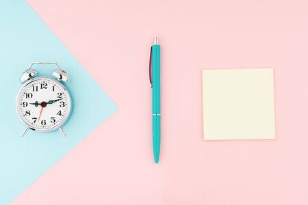 Metal vintage alarm clock with office pen and yellow sticky notes on colorful paper background. Work and planning time flat lay conceptの写真素材