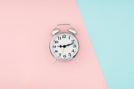 Metal vintage alarm clock on of colorful paper background. Time and planning minimal flat lay conceptの写真素材