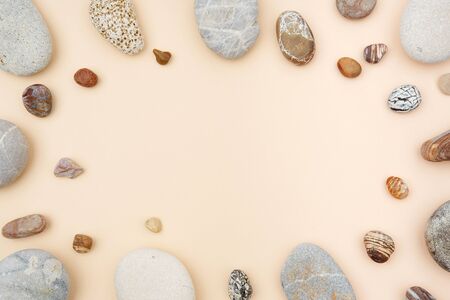 Mix of rounded multicolor textured stones on beige paper background . Flat lay with copy spaceの写真素材