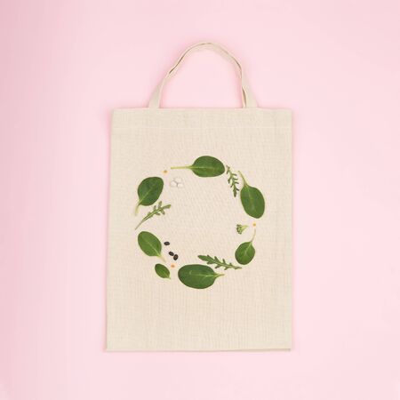 Canvas eco bag with creative green composition made of green spinach leaf, rucola and bean . Flat lay view on pink backgroundの写真素材