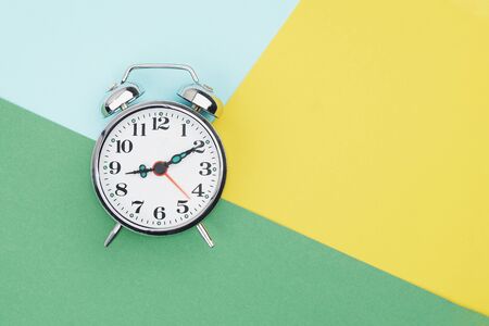 Metal vintage alarm clock with on sections of colorful paper background. Work and planning time flat lay conceptの写真素材
