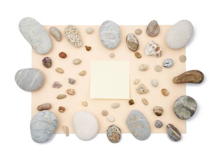 Sticky notes in the middle of mix of rounded multicolor textured stones on beige paper background . Isolated flat lay with copy spaceの写真素材