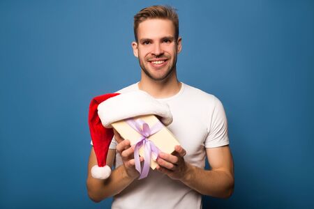 happy young man holding santa hat and present isolatedの写真素材