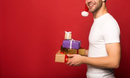 partial view of young smiling man in santa hat holding gifts isolatedの写真素材