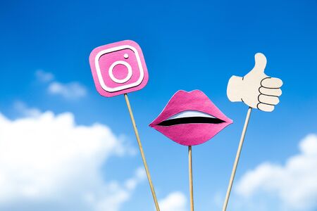 KYIV, UKRAINE - MAY 25, 2019: Instagram logo, lips and thumb up sign on sticks on blue sky backgroundのeditorial素材