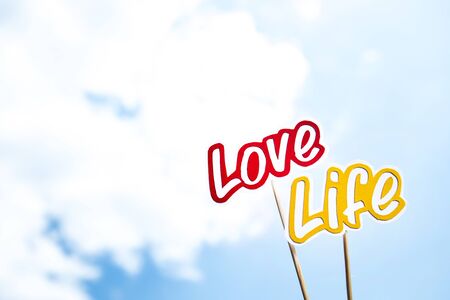 paper cut words love and life on sticks on blue sky