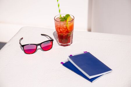 fresh cocktail near stylish sunglasses and passports on white surfaceの写真素材