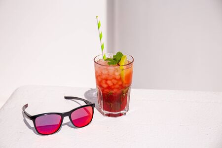 fresh cocktail near stylish sunglasses on white surfaceの写真素材