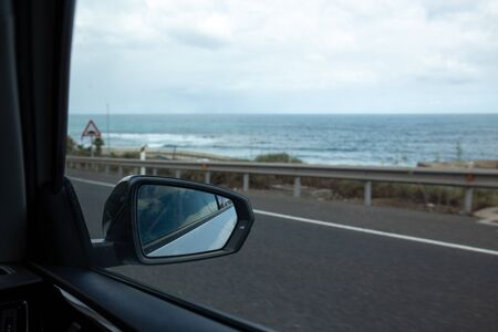 selective focus of side mirror on car and road near Atlantic ocean in Maspalomas, Gran Canaria