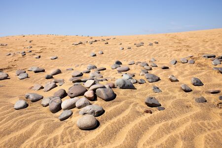 pebbles on sand hills against clear blue sky in Maspalomas, Gran Canaria
