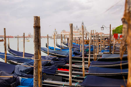 VENICE, ITALY - SEPTEMBER 9, 2019: traditional Venetian gondolas on water in wooden berth in Venice, Italy.のeditorial素材