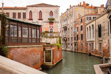 city street with buildings on water channel in Venice, Italy.