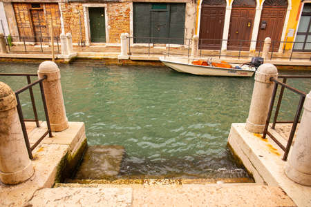 VENICE, ITALY - SEPTEMBER 9, 2019: steps in small water channel with boat near ancient building in Venice, Italy.のeditorial素材