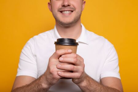 cropped view of smiling man with coffee to go on yellow backgroundの写真素材