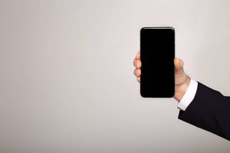cropped view of businessman presenting smartphone with blank screen on grey backgroundの写真素材