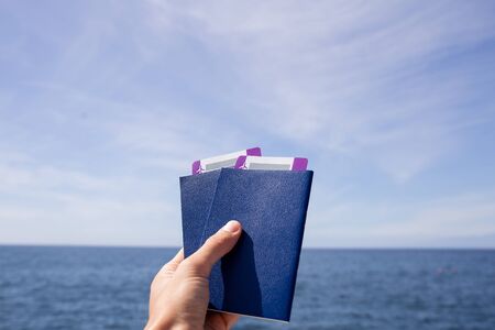 selective focus of male hand with passports and air tickets against Atlantic ocean and blue sky in Maspalomas, Gran Canariaの写真素材