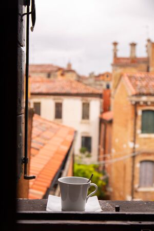 view from window on Venetian ancient buildings with cup of coffee of windowsill in Venice, Italy.の写真素材