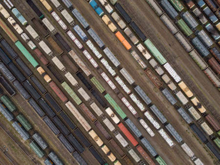 Cargo trains close-up. Aerial view of colorful freight trains on the railway station. Wagons with goods on railroad. Heavy industry. Industrial conceptual scene with trains. Top view from flying droneの写真素材