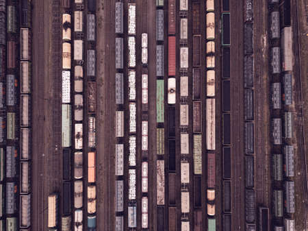 Aerial view of freight trains. Railway cargo wagons with goods on railroad. Top view of colorful...