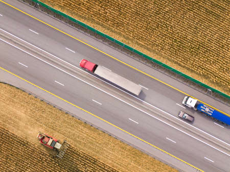 two trucks on the highway. cargo delivery driving on asphalt road along the agriculture fields. seen from the air. Aerial view landscape.の写真素材