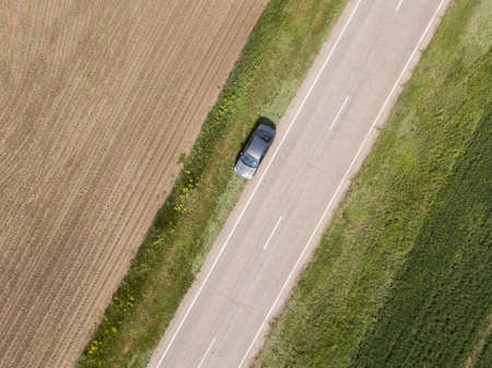 Aerial view of green summer field with a road. Captured from above with a droneの写真素材