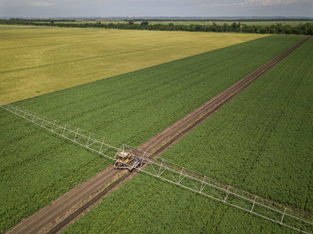 Aerial top down image of tractor spraying soil and young crop in springtime in fieldの写真素材