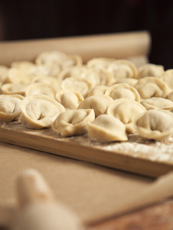 Dumplings and parsley - russian pelmeni. Cook dumplings. Pasta ravioli over wooden desk. Baking.の写真素材