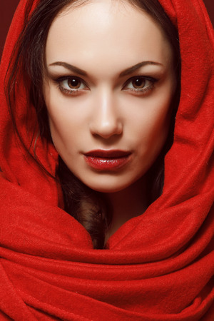 beautiful face of a young woman in a red scarf and with perfect makeupの写真素材