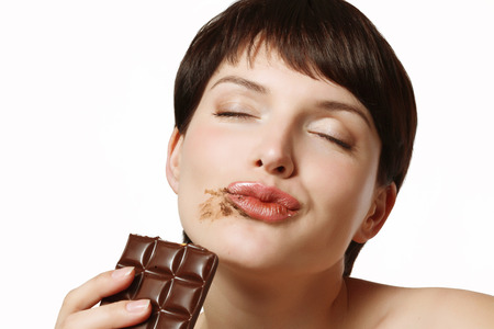 young and beautiful woman eating a delicious dark chocolateの写真素材