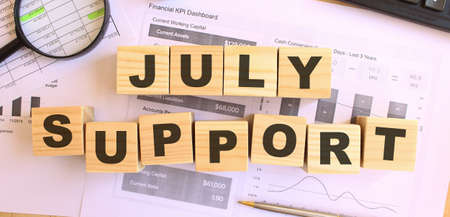 Wooden cubes with letters on the table in the office. Text JULY SUPPORT. Financial concept.