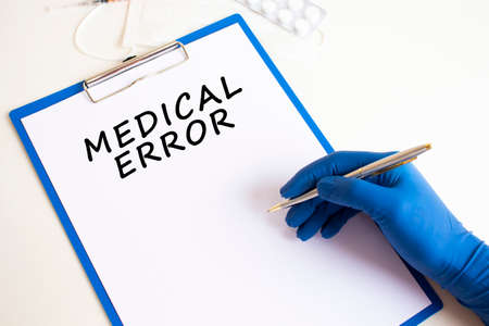 Female doctor's hand in a medical glove makes an inscription in a document. Medical concept.の写真素材