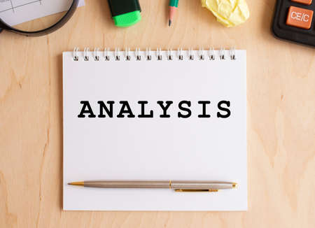 Notepad with text ANALYSIS on a wooden table, near calculator and office supplies. Business concept.の写真素材