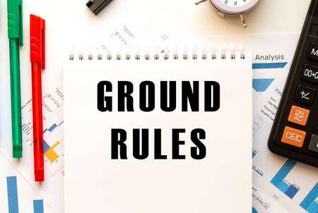 Notepad with the text GROUND RULES on a color financial chart. Pen, calculator on the office table.の写真素材