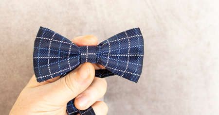 The groom holds in his hands a blue-and-white polka-dot bow tie, classic with textile.