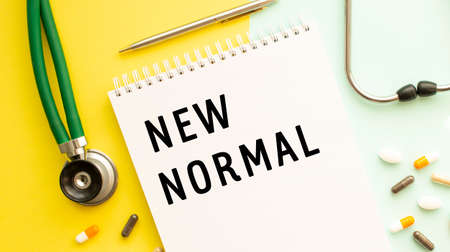 Text NEW NORMAL on notebook with stethoscope and pen on yellow background. Medical concept.