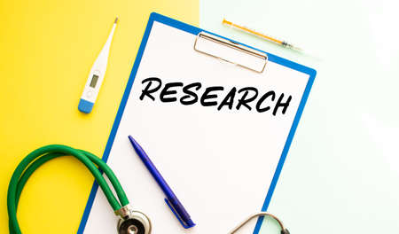 Text RESEARCH on a letterhead in a medical folder. Stethoscope, thermometer on a colorful...
