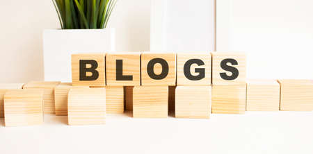 Wooden cubes with letters on a white table. White background with photo frame, house plant.