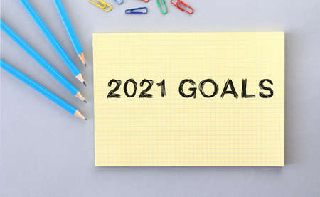 2021 GOALS text in notebook on gray background next to pencils and paper clips. Concept.の写真素材