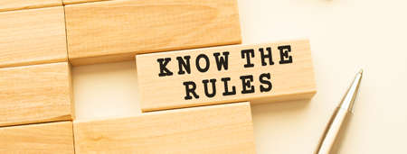 KNOW THE RULES text on a strip of wood lying on a white table with a metal pen. Concept.の写真素材