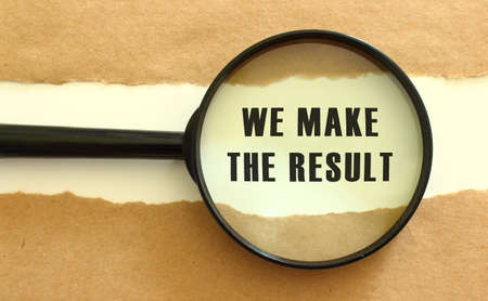 The magnifying glass reveals the WE MAKE THE RESULT text appearing behind the torn brown paper. Business conceptの写真素材