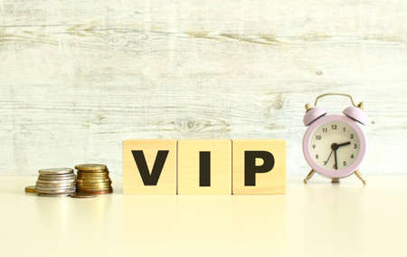 There are three wooden cubes with letters on the table next to the coins. The word VIP. On a gray...