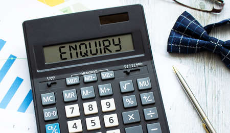 A calculator labeled ENQUIRY lies on financial documents in the office. Business concept.の写真素材