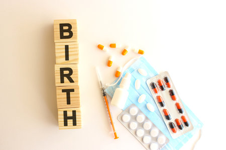 The word BIRTH is made of wooden cubes on a white background with medical drugs and medical mask.の写真素材