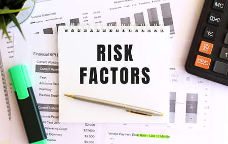 Notepad with text RISK FACTORS on a white background, near marker, calculator.の写真素材