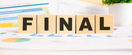 FINAL word on wooden cubes. The background is a business graphs. Business and finance conceptの写真素材