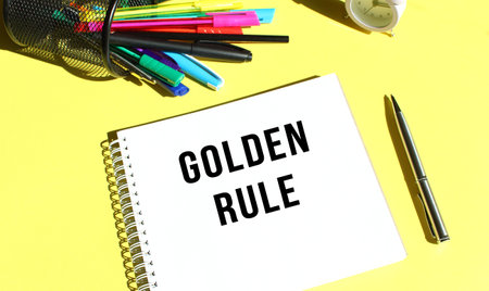 Notepad with text GOLDEN RULE with stationery. Yellow background color.の写真素材